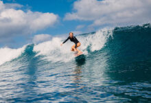 Woman surfer rides on crashing wave on a sunny day, surfing in ocean.