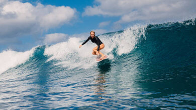 Woman surfer rides on crashing wave on a sunny day, surfing in ocean.